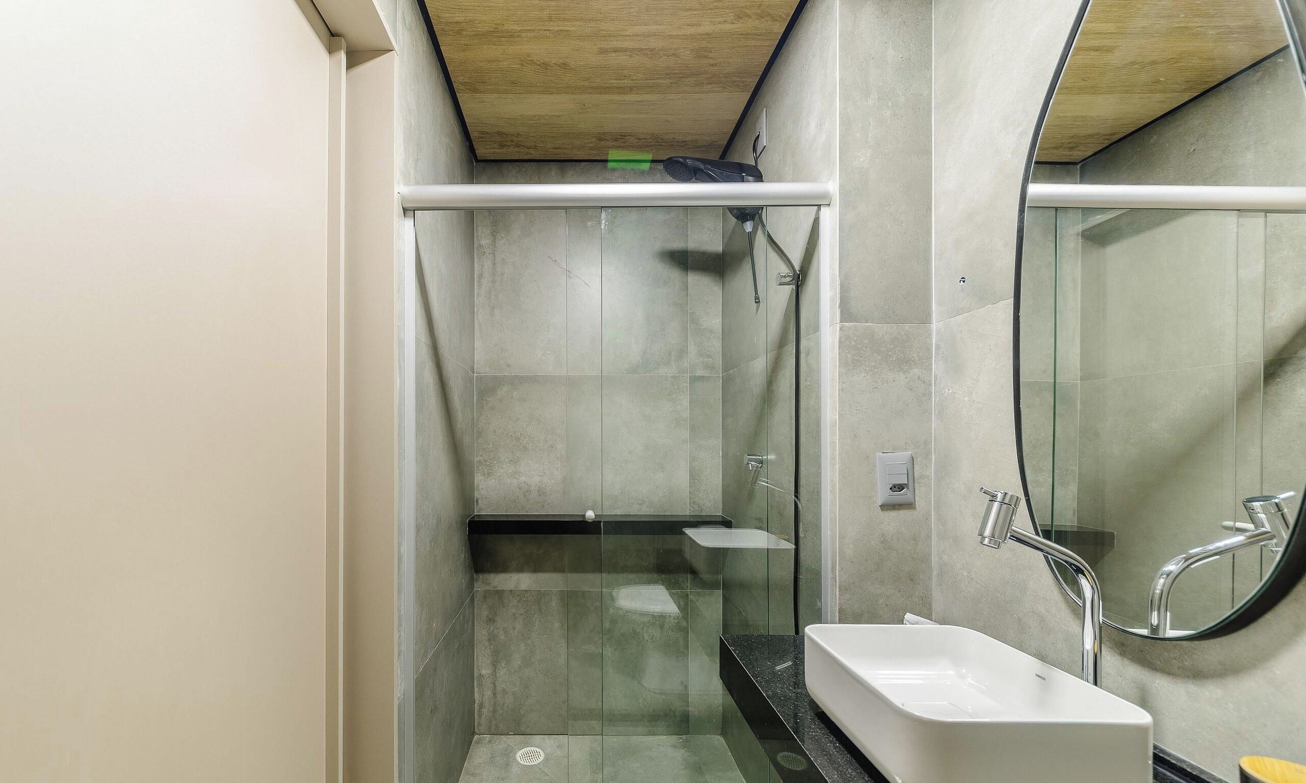 A modern bathroom with a glass shower enclosure, a white sink, and a mirror.