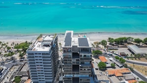 A high-rise building with multiple floors, a rooftop pool, and a view of the ocean. - Nwts - Studios With Side sea View in Maceio IV (Maceió)