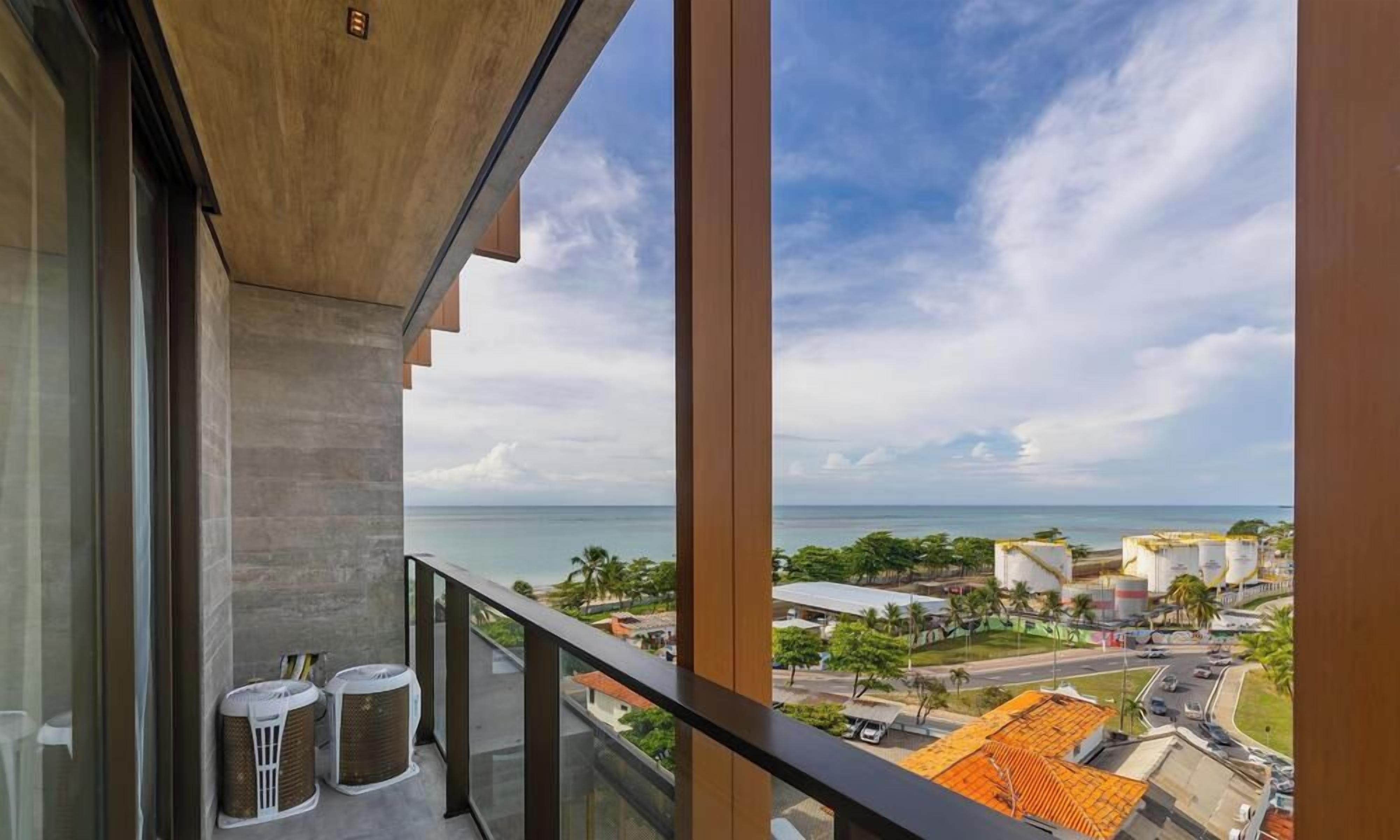 A balcony with a view of the sea and industrial buildings.