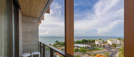 A balcony with a view of the sea and industrial buildings.
