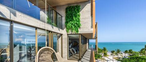 A modern building with a glass balcony overlooking a beach.