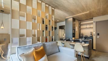 Una sala de estar moderna con un sofá, un comedor con sillas, una cocina con mostrador y un panel de madera con recortes.