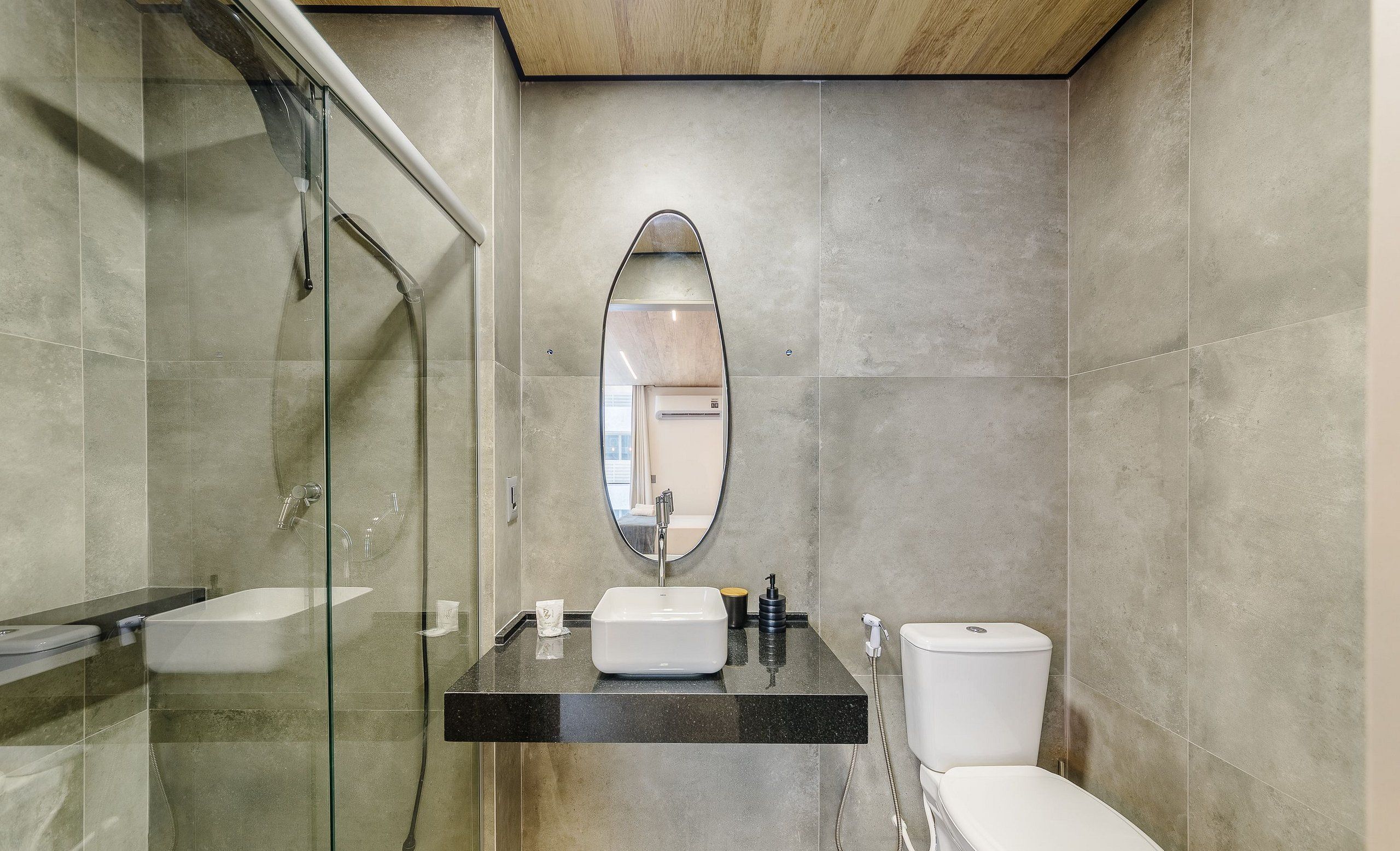 A modern bathroom with a glass shower enclosure, a vanity with a sink, mirror, and a toilet.