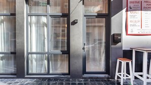 A modern building facade with large windows, a door with a handle, and a menu board on the right.