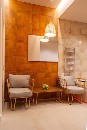 A modern room with a wooden wall, a whiteboard, wicker chairs, a small table with fruit, and a hanging light fixture.