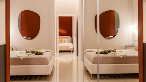 A modern hotel room with two beds, a large mirror, and a clean, minimalist design.