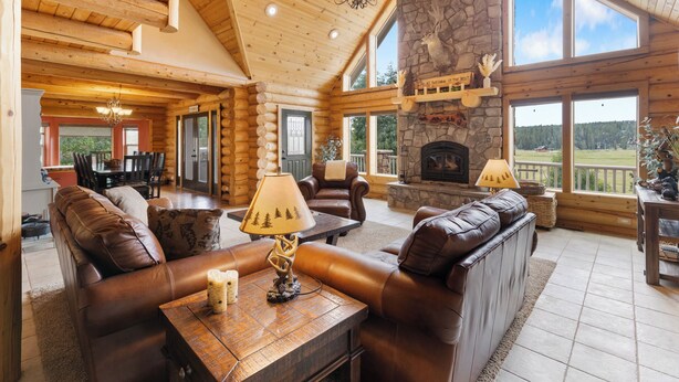 A log cabin interior with a stone fireplace, leather sofas, and a chandelier. - Fantastic 5-bedroom Cabin with Wi-Fi in Duck Creek Village  NEW LISTING (Duck Creek Village)