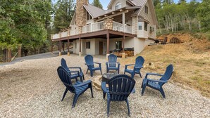 A log cabin with a stone chimney, a covered porch, and outdoor seating with Adirondack chairs. - Fantastic 5-bedroom Cabin with Wi-Fi in Duck Creek Village  NEW LISTING (Duck Creek Village)