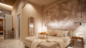 A bedroom with a large bed, a side table, a mirror, and a wall mural.
