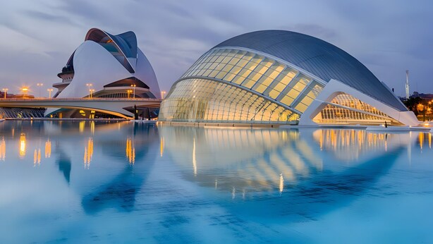 A modern architectural building with a large glass dome and a reflective pool in front.