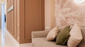 A modern hotel lobby with a beige sofa, a wall mural, and a light fixture.