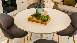 Cocina moderna con microondas, horno y cafetera. Hay una mesa de comedor con una bandeja de manzanas verdes y una vela.