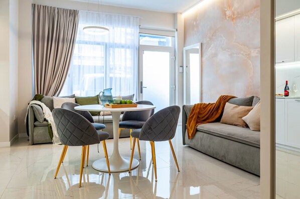 A modern living room with a sofa, two chairs, a coffee table, and a kitchen area with a counter and cabinets.