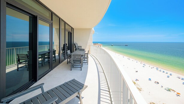 Ein Balkon mit Blick auf den Strand, einem Tisch und Stühlen sowie einem Geländer.