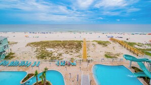 Un complejo turístico en la playa con piscina, tobogán de agua y sombrillas.