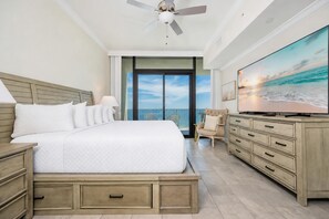 A bedroom with a bed, a dresser, a TV, and a balcony with a view.