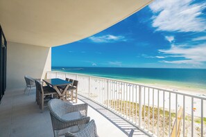 A balcony with wicker furniture overlooking a beach.