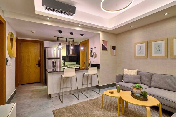 A modern kitchen with a central island, bar stools, a sofa, and a coffee table.