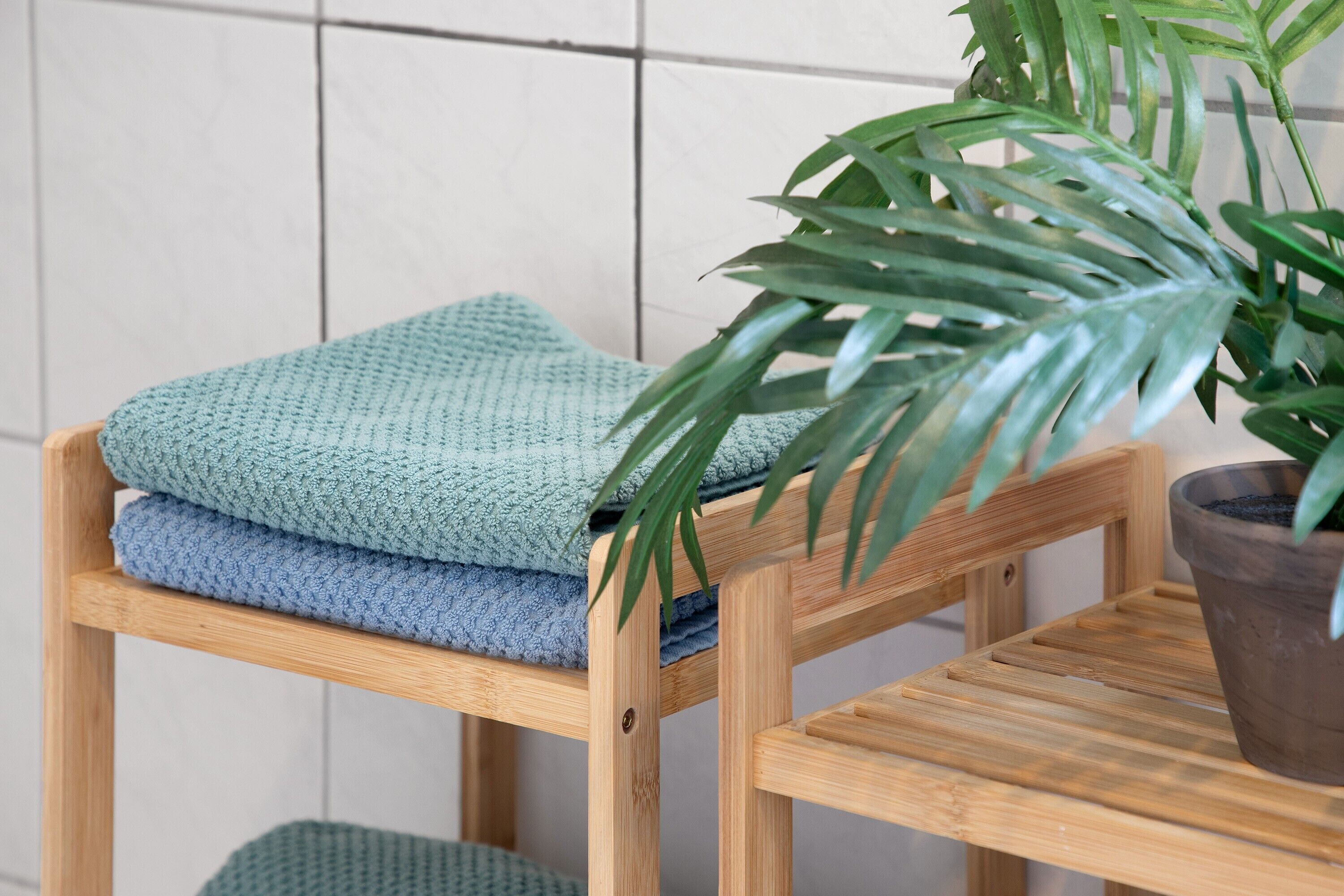 Une chaise en bois, avec des serviettes pliées et une plante en pot.