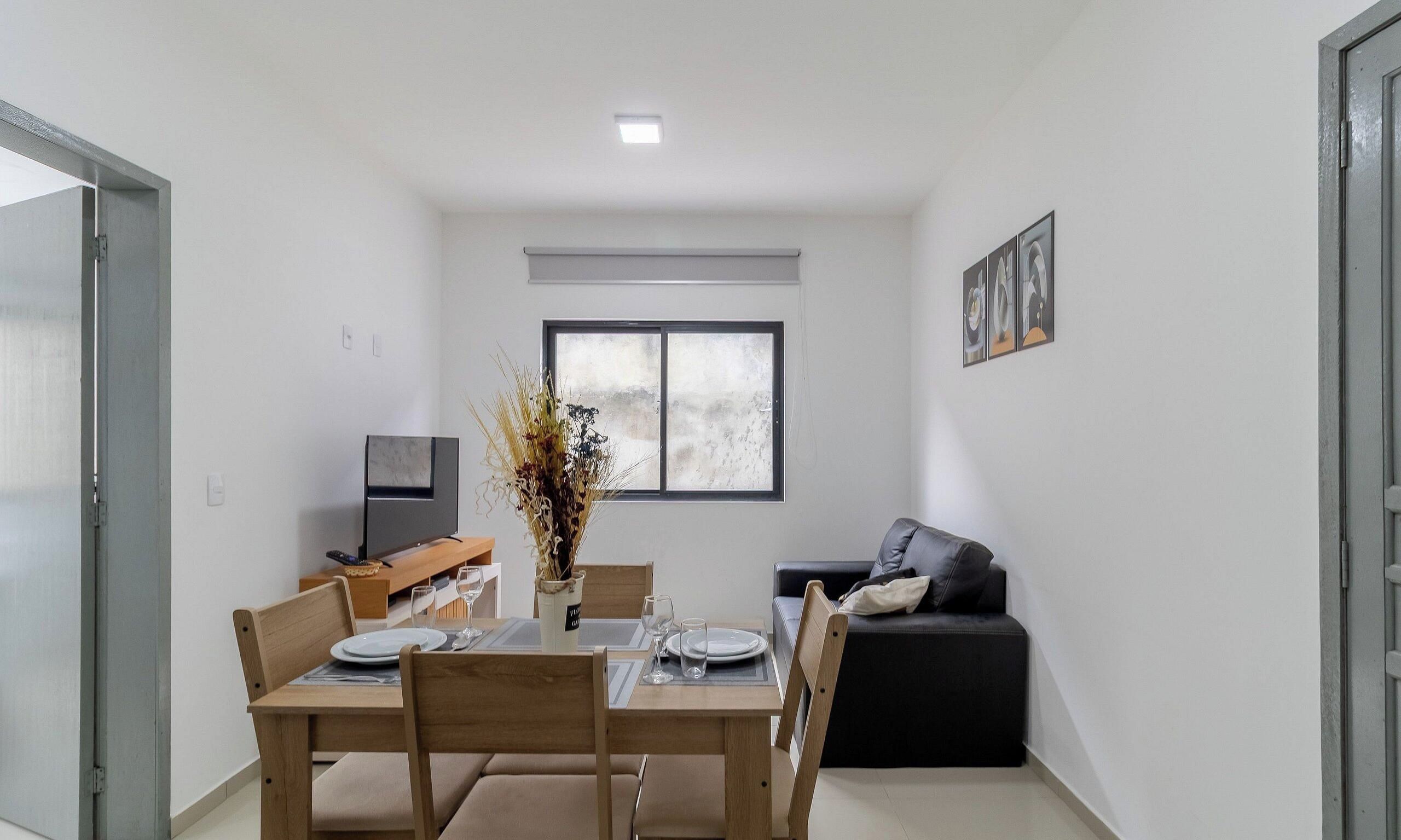 A compact living space with a dining area, a sofa, a television, and a window.