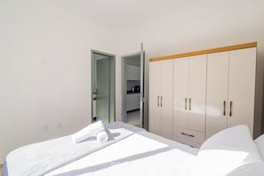 Un dormitorio con cama, armario y puerta abierta al baño.