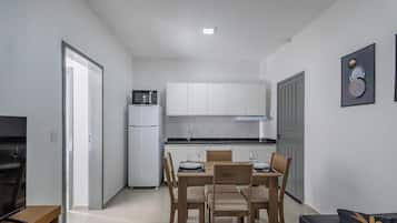 A compact kitchen with white cabinets, a refrigerator, and a microwave.