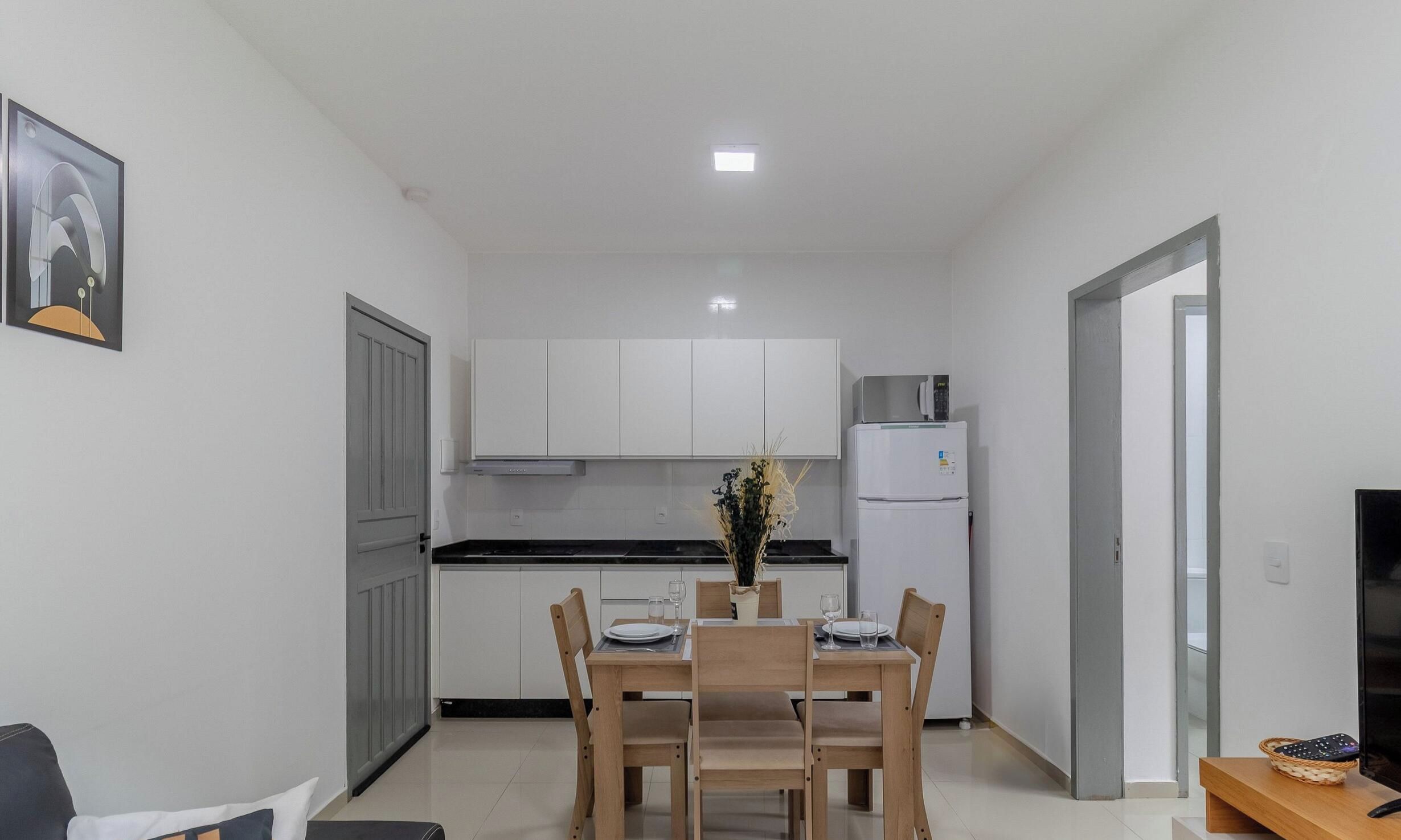 Une cuisine compacte avec des meubles blancs, un réfrigérateur et une table à manger pour deux personnes.