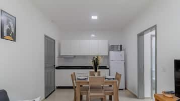 Une cuisine compacte avec des meubles blancs, un réfrigérateur et une table à manger pour deux personnes.