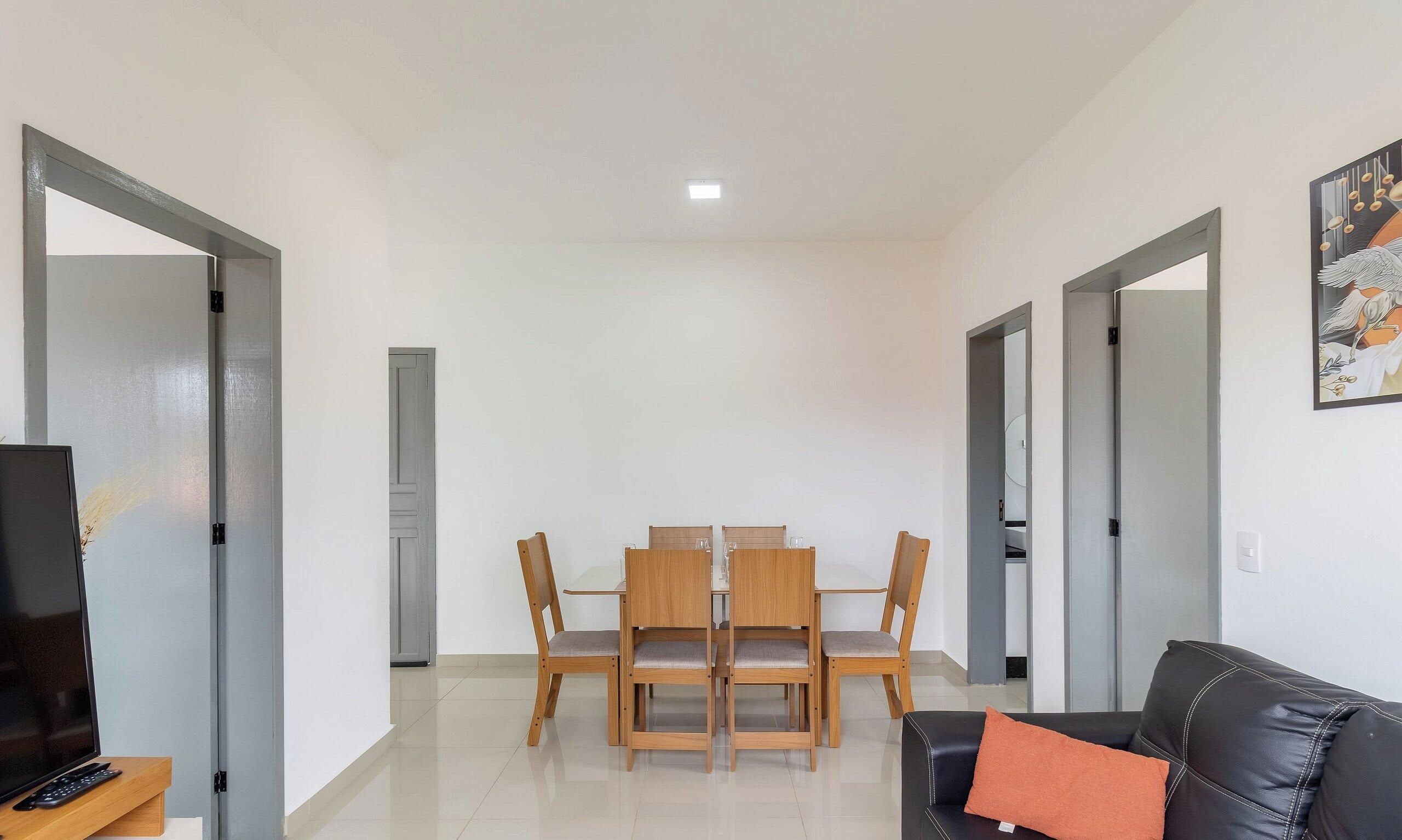 Una sala de estar moderna con comedor, que incluye un televisor de pantalla plana, un sofá de cuero y una mesa de comedor con sillas.