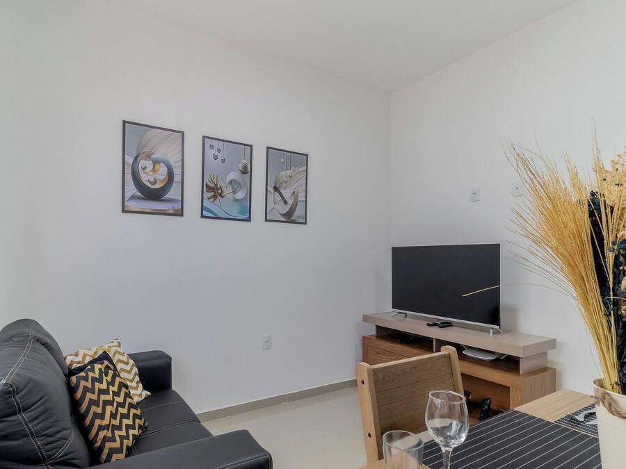 A modern living room with a sofa, a flat-screen TV, and three abstract paintings on the wall.