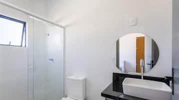 Ein Badezimmer mit Toilette, Waschbecken, Spiegel und Dusche.