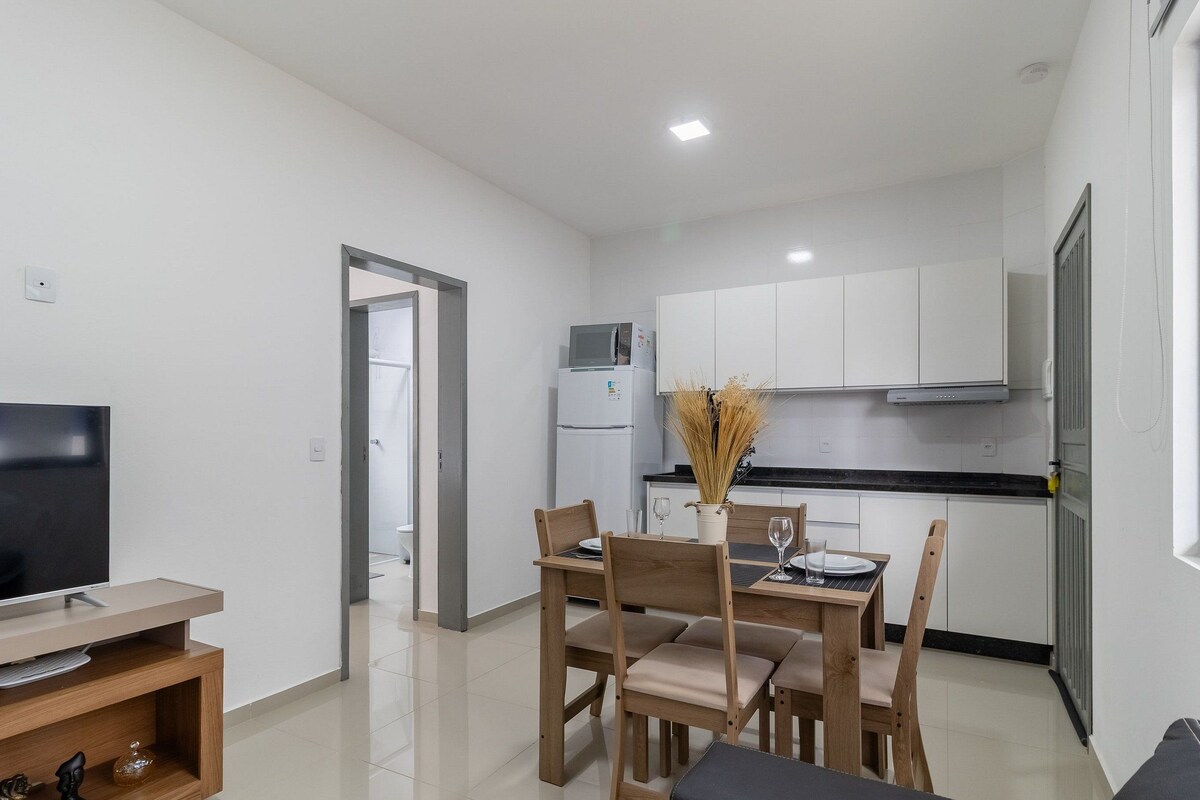 A compact kitchen with white cabinets, a microwave, and a refrigerator.