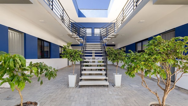 A modern building with a central staircase, potted plants, and a skylight. - Beautiful Apartments in Campeche - Floripa - SCO (Florianópolis)