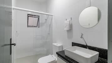 Un baño con ducha, inodoro, lavabo y espejo.