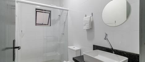 Une salle de bain équipée d’une douche, de toilettes, d’un lavabo et d’un miroir.