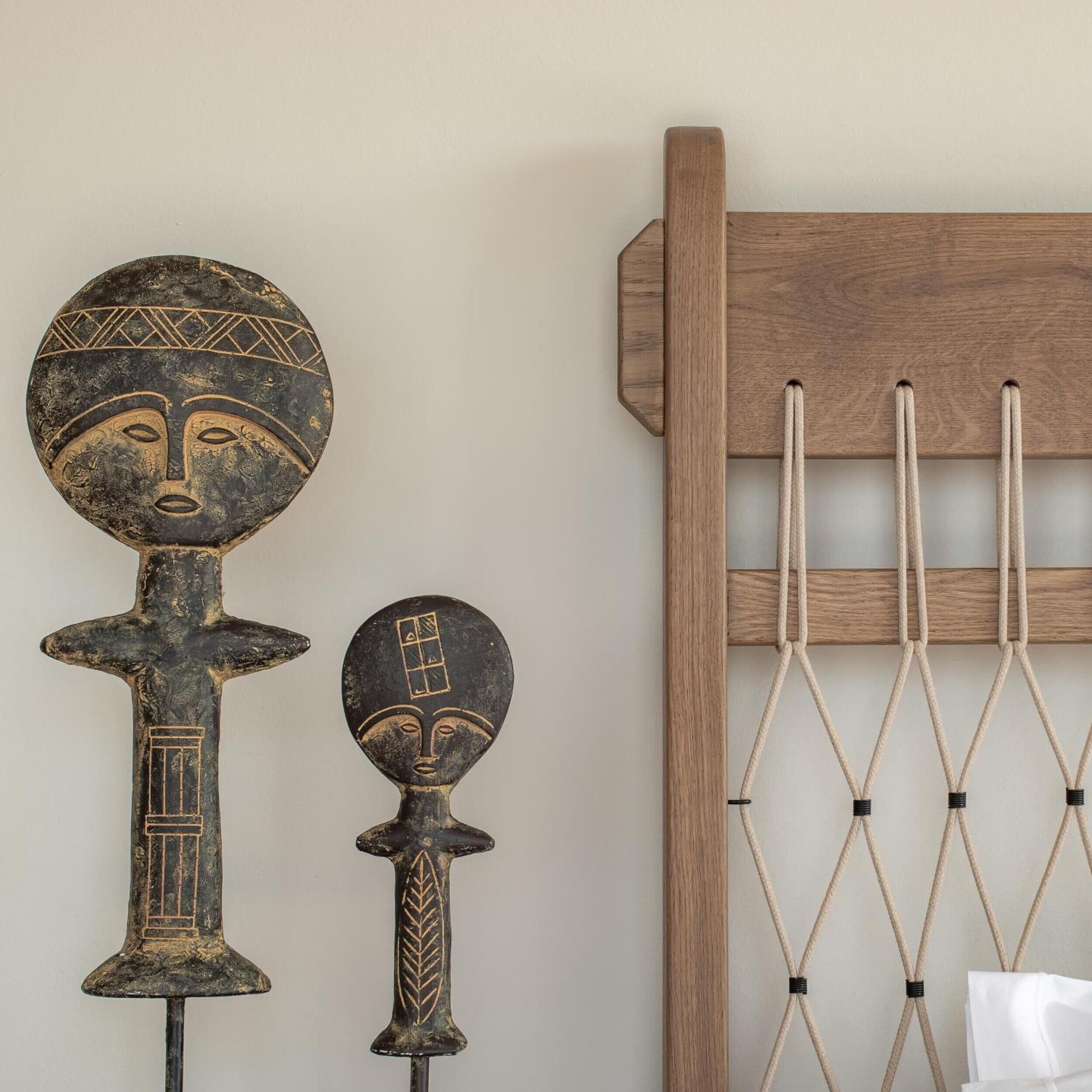 A wall with two wooden sculptures and a wooden rack with ropes.