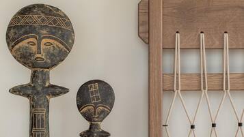 A wall with two wooden sculptures and a wooden rack with ropes.