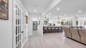 A spacious kitchen with a central island, a dining area with bar stools, and a large sofa.