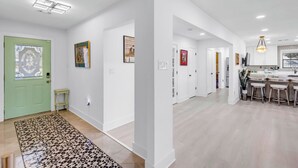 A modern interior with a kitchen area, dining space, and a hallway with artwork.