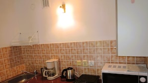 Una cocina equipada con microondas, cafetera, hervidor y un lavabo.