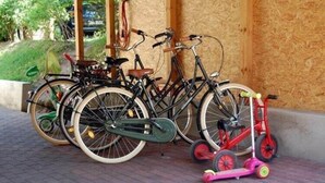 Bicicletas y un patinete rosa aparcados en una zona pavimentada.