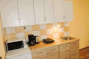 A kitchen with white cabinets, a microwave, a coffee maker, and a sink.