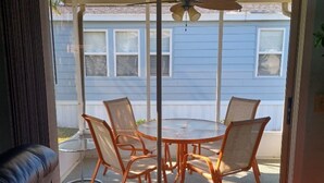 Une porte-fenêtre coulissante donnant sur un patio extérieur avec une table ronde et quatre chaises.