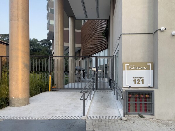 A gated entrance to a building with a sign indicating 'VERDE PANORAMA' and 'Rua Miragais 121'. - Ver.de Panorama (São Paulo)