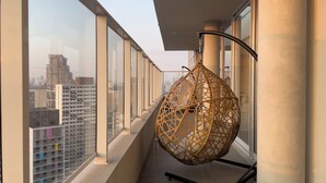 A balcony with a hanging chair, large windows, and a city view. - Ver.de Panorama (São Paulo)