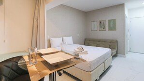 A hotel room with a bed, a sofa, a desk with a glass, and a chair. - Ver.de Panorama (São Paulo)