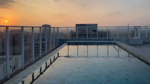 A rooftop infinity pool with a cityscape view during sunset. - Ver.de Panorama (São Paulo)