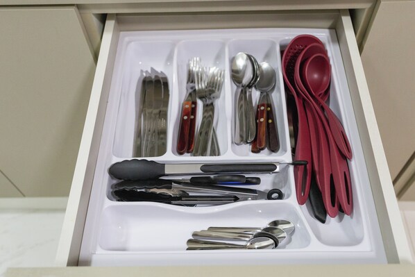 A drawer with utensils neatly organized, including forks, knives, spoons, and tongs.