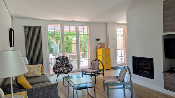 A living room with a sofa, two chairs, a small table, a lamp, a television, a fireplace, and a yellow cabinet. - Quiet family home with garden and small pool. Close to beach and shops. (Le Grau-du-Roi)
