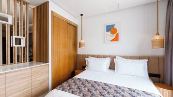 Una habitación de hotel moderna con una cama grande, un armario de madera y una obra de arte colgada en la pared.